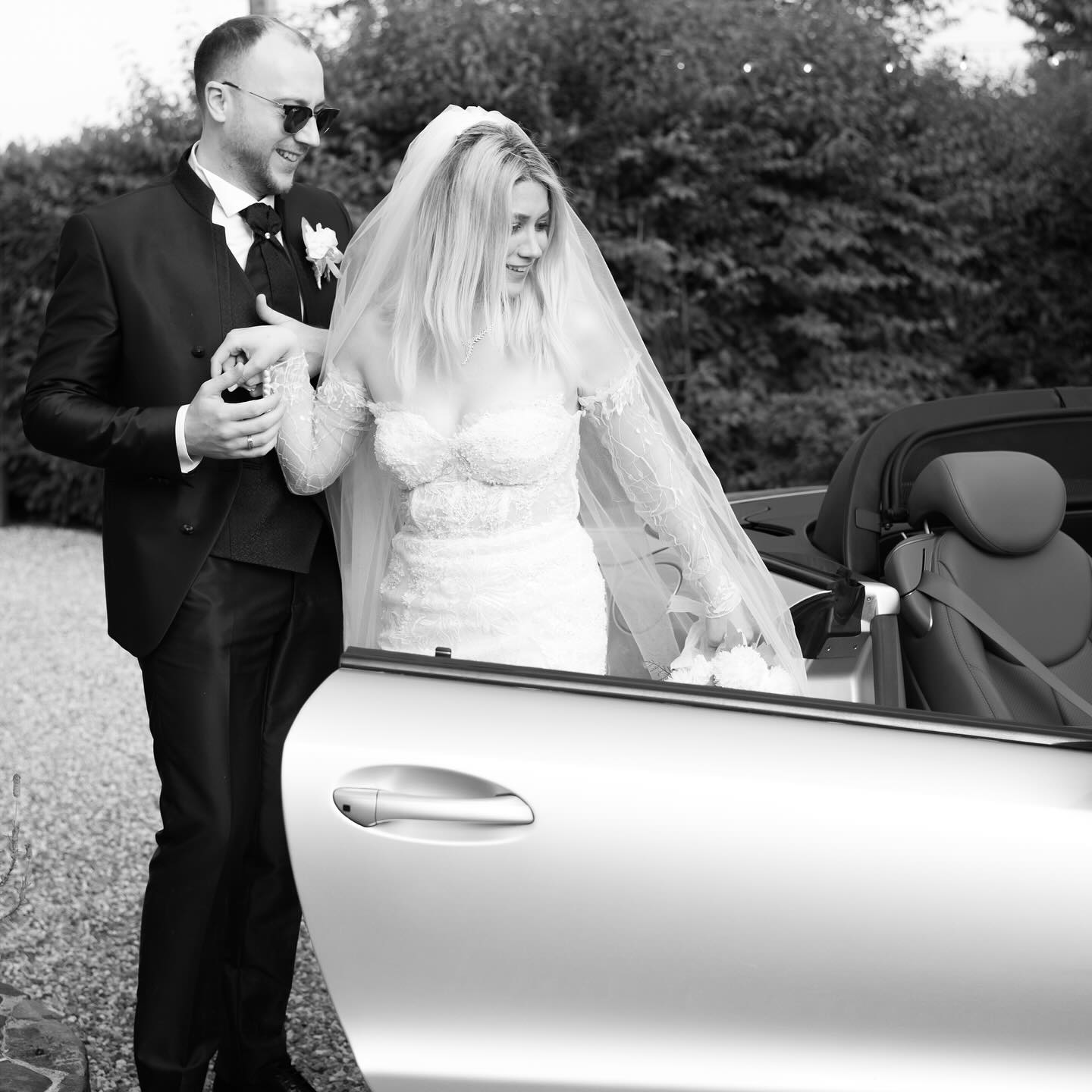 Sposa che sale in auto d'epoca sorretta dallo sposo